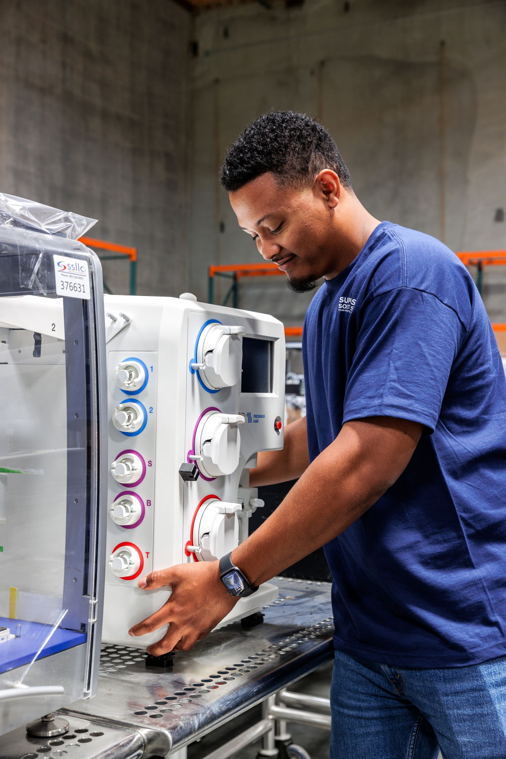 Technician performing a detailed assessment of lab equipment for resale potential in a warehouse setting.